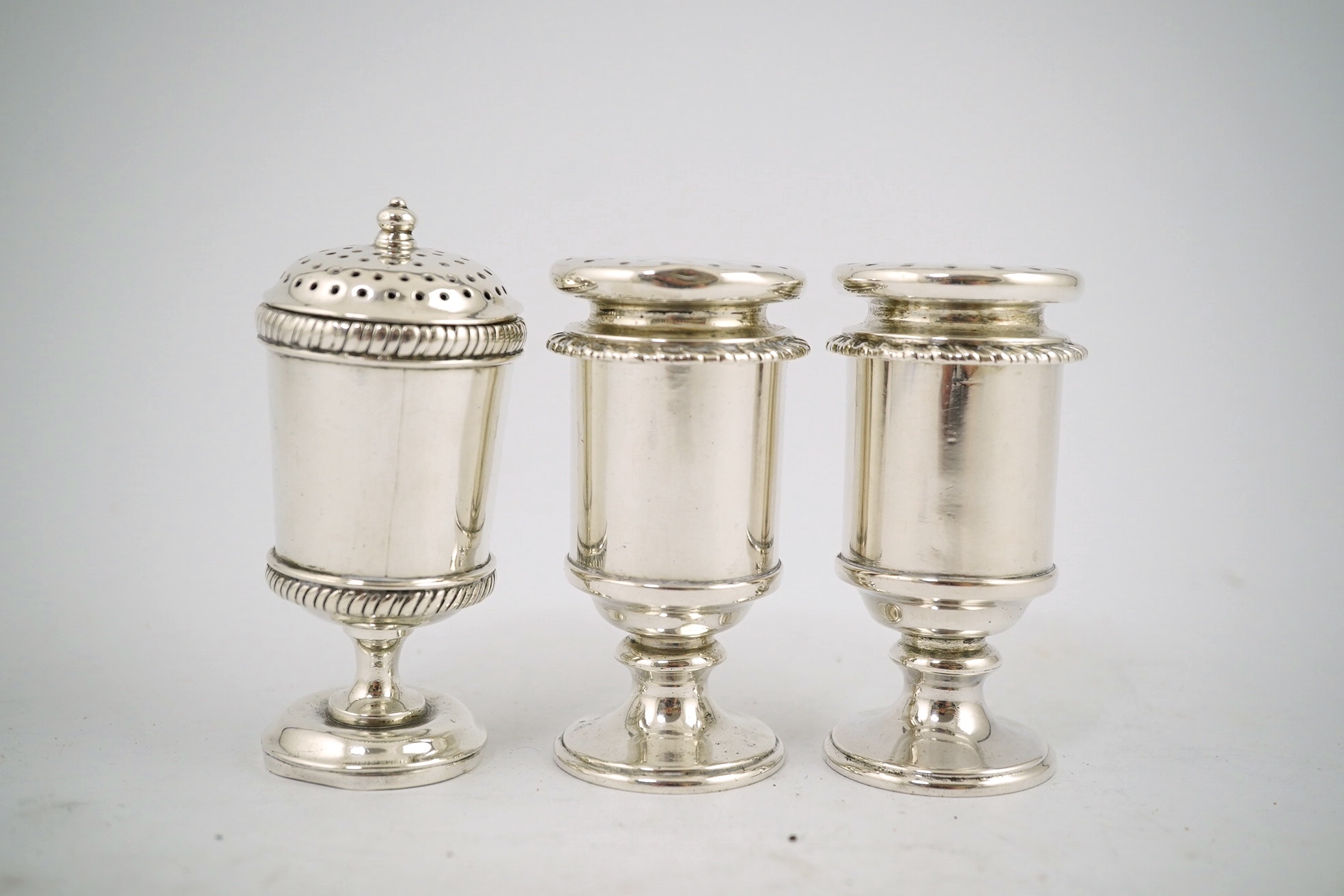 A pair of Hamilton & Co. Anglo-Indian silver pepper pots and a similar unmarked pepper pot, c.1800, tallest 9.4cm, 299g gross. Condition - fair